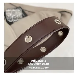 Detail of deep brown leather adjustable shoulder strap with silver eyelets and stitching