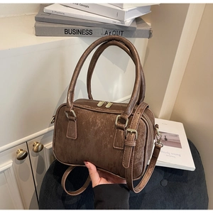 Close-up of brown textured Boston bag with golden hardware and detachable strap