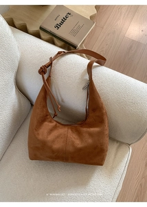 Close-up of brown suede hobo bag with knot detail and fine stitching on a sofa