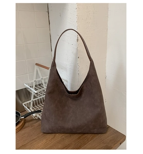 Macro detail of deep brown suede hobo bag texture and seamless shoulder strap on wood table