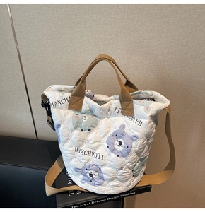 Detail of quilted bucket bag featuring cute bear patterns and adjustable brown straps