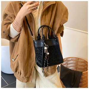 Détail du sac cabas noir avec empiècement léopard, poignée nouée et breloques déco