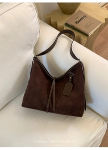 Vue détaillée d'un sac hobo en daim marron foncé avec frange en cuir et large bandoulière