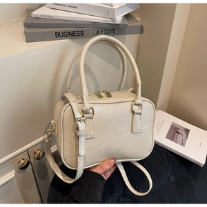 Close-up of cream Boston bag with embossed leather texture and gold hardware details