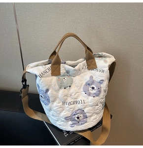 Detail of white quilted tote bag featuring purple rabbit print and brown webbing handles