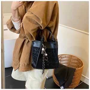 Détail du sac seau léopard avec poignées nouées et accessoires de charme bohème