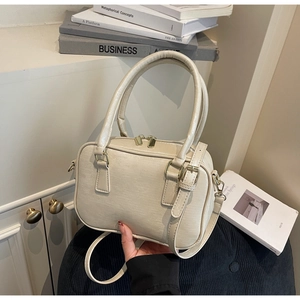 Close-up of cream textured faux leather bag with dual zippers and light gold hardware