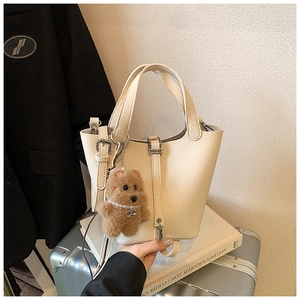 Detalle del bolso de cubo con patrón de lichi, oso de peluche y cadena de perlas