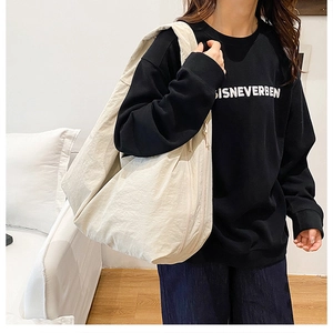 Detail der cremeweißen Canvas-Hobo-Tasche mit minimalistischer Halbmondform und Textur