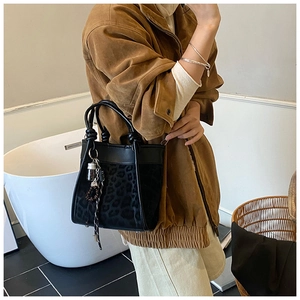 Détail du sac seau à motif léopard avec poignée nouée et breloque à pompons