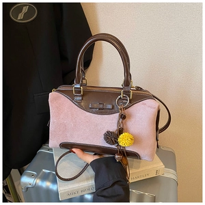Detail of pink suede and brown leather Boston bag with decorative bow and tassel charm