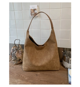 Detailed close-up of brown suede hobo tote bag with a soft vintage texture on wood