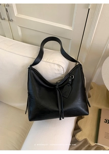 Détail de sac cabas vintage en cuir noir mat avec longues franges et étiquette logo