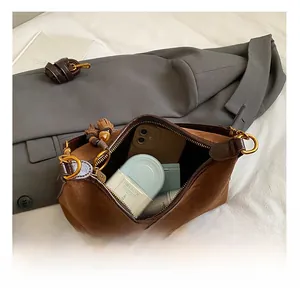 Interior view of brown suede crescent bag showing storage space for phone and makeup
