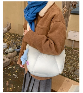 Borsa a gnocco bianca trapuntata con ciondolo blu indossata da modella in autunno