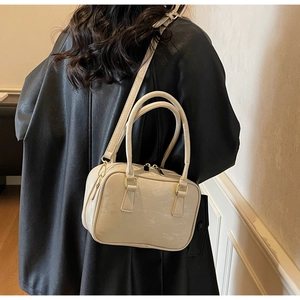 Rear view of cream Boston handbag with cross-texture finish and adjustable strap