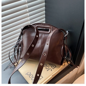 Detail view of chocolate brown tote bag with side tassels and silver grommet wide strap