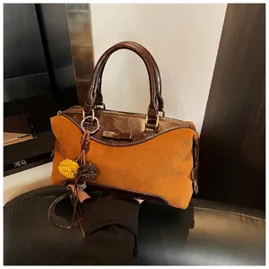 Detailed shot of brown suede handbag featuring leather trim and decorative bow accent