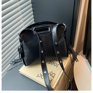 Detail of black glossy fringe handbag with hollow handle and metal eyelet accents