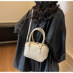 Detail of cream Boston handbag showing fine grain texture and golden metal hardware