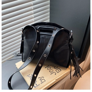 Detail view of the black PU leather handbag with silver grommets and long tassel charms