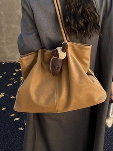 Vintage brown leather tote bag with knit pendant shown on shoulder in autumn setting