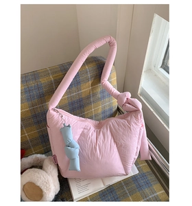 Dettaglio della borsa nuvola rosa imbottita con manico annodato ed etichetta moda su sfondo