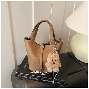 Detalle de bolso cubo marrón con textura lichi y un colgante de peluche de perrito