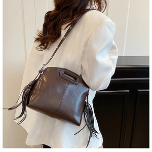 Detail of dark brown faux leather bag with long side tassels and a cutout handle