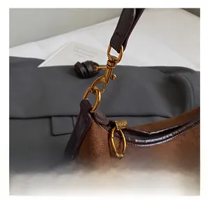 Detail shot of golden alloy hooks and leather edges on a vintage brown suede bag
