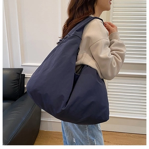 Seitenansicht der großen dunkelblauen Canvas-Tasche in Halbmondform an der Schulter