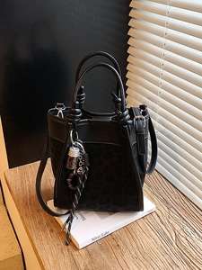 Sac seau noir élégant avec motif léopard et poignée nouée posé sur un livre