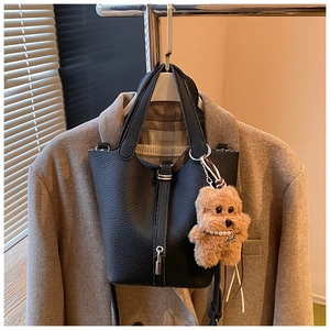 Detalle de bolso cubo de cuero granulado negro con cierre plateado y adorno de peluche