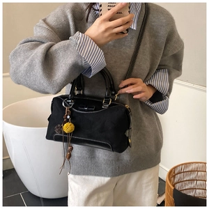 Detail of black suede patchwork Boston bag with bow accent and fuzzy charm accessory