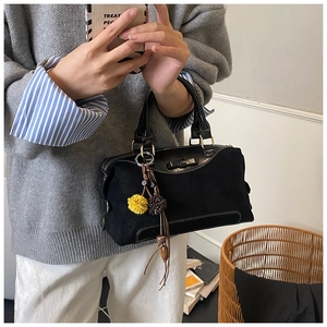 Detail of vintage black Boston bag featuring leather bow and pompom charms on handles
