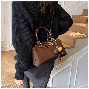 Detail of dark brown Boston bag with suede patchwork, bow decor and plush charms