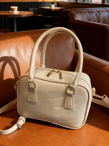 Creamy beige Boston bag in epi leather with gold hardware on a brown sofa