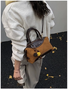 Detailed macro of vintage suede contrast bag with soft pompom accessory in autumn setting
