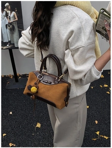 Detail of vintage brown suede Boston bag with floral charm during an autumn photoshoot