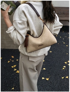 Detailed texture of suede hobo bag with leather trim and fringe tassel decoration
