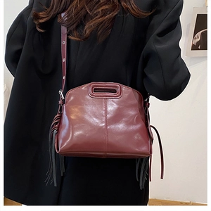 Detail of burgundy leather handbag with rectangular handle and stylish long side tassels