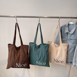 Detailed close-up of corduroy tote bags with Nice embroidery in three classic colors