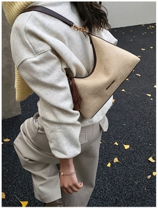 Detailed macro view of the beige suede baguette bag with brown fringe and brand logo