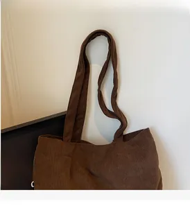 Close-up of deep brown corduroy tote bag showing its ribbed fabric texture and strap