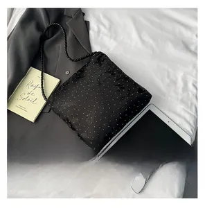 Flat lay of black studded shoulder bag with woven strap next to grey blazer and tablet