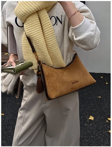 Close-up of brown suede baguette bag with tassel detail and vintage metal hardware
