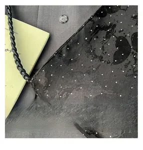 Detail of butterfly print bag with dotted rhinestones and woven leather strap