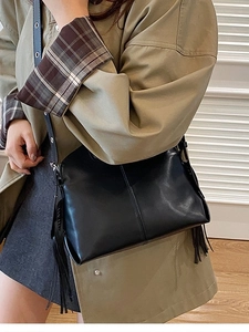 Classic black leather crossbody bag with vertical stitching and decorative tassels
