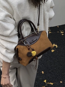 Vintage suede Boston handbag for women featuring plush ball charm on autumn leaves