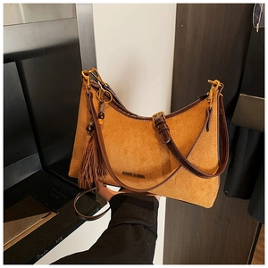 Detail of mustard yellow suede baguette bag featuring a leather tassel and brand logo